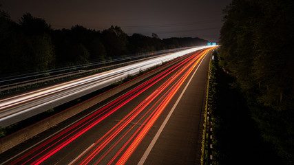 Fototapeta na wymiar Langzeitbelichtung auf der Autobahn. Nachtlichter, Stadtlichter, Geschwindigkeit, Transport, Traffic, Autos in Bewegung, Fahrbahn, Road