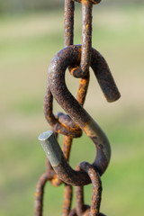 Old rusty chain, chain links, and large s-hook, with a green bokeh background, close-up, Block Island, RI