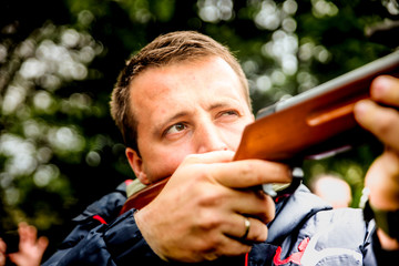 a man with a rifle stands for a corner building in ambush waiting for his target