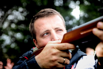a man with a rifle stands for a corner building in ambush waiting for his target