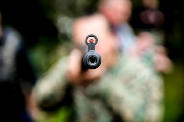 a man with a rifle stands for a corner building in ambush waiting for his target