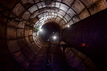 Round concrete underground tunnel of heating duct system with rusty pipes