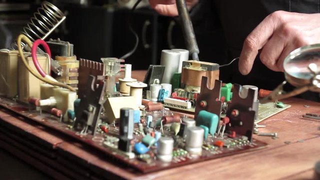 master soldering radio components on the desktop, close-up