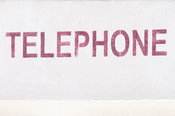 Inscription téléphone écrite en rouge sur un mur blanc