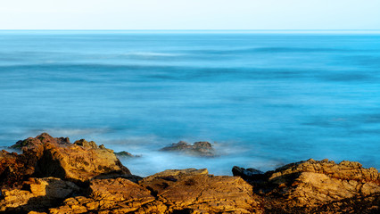 Long exposure view of the ocean near Pebble Beach, Monterey, California,, USA, on the 17-mile drive route in the winter of 2019, in the sunrise- large blue copy space 