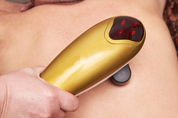 Senior male patient receive electrostatic therapy procedure on his back. Electrostimulation massage...