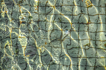 Coin in the fountain background of tiles and a coin underwater with bubbles on the surface