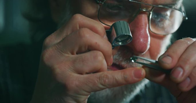 Slow motion macro close up of experienced goldsmith controlling a quality of precious gem, selected for making jewels in workshop. Shot in 8K. Concept of jewelry,luxury,goldsmith, diamonds, brilliance