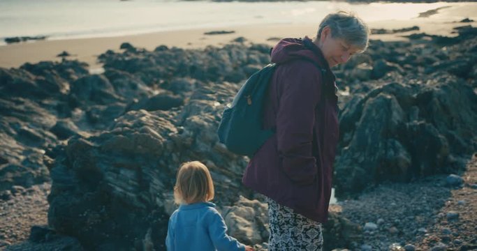 Toddler walking on beach with mother and grandmother at sunset