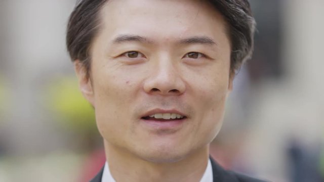 Close portrait of Asian male talking to camera, in slow motion