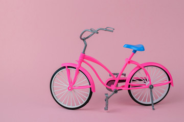 Red bike with blue saddle on pink background.