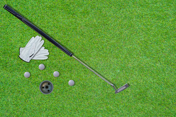 High angle view of Putter golf, golf club, gloves  golf bal and hole with beautiful green lawn...
