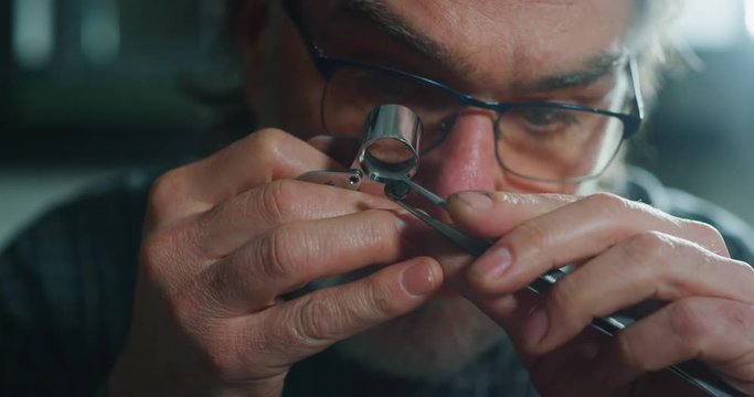 Slow motion macro close up of experienced goldsmith controlling a quality of precious gem, selected for making jewels in workshop. Shot in 8K. Concept of jewelry,luxury,goldsmith, diamonds, brilliance