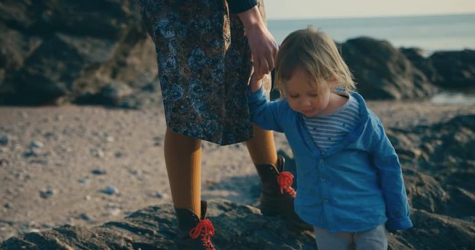 Little toddler leading his mother and grandfather on coastal walk