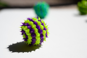 purple and green striped ball with spikes on white surface