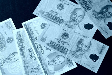 Vietnamese dongs on a dark background close up. Blue color toned