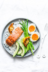 Healthy delicious balanced lunch - baked salmon, rice, asparagus, avocado and boiled egg on a light background, top view