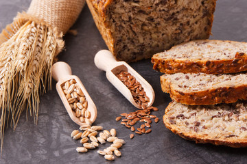 Wholegrain bread with ingredients for baking and ears of rye or wheat grain