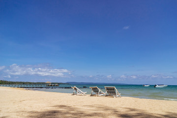 Three folding beach chairs on the beach with sea and bright sky in the background at Koh Mak in Trat, Thailand. Seasonal Vacation. Background with copy space.
