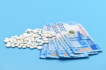 Russian two thousand rubles and round white pills on a blue background