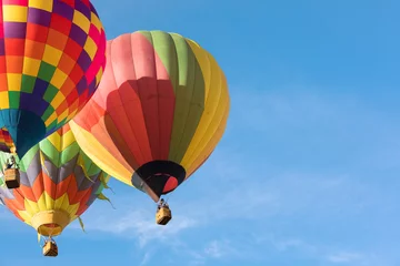 Cercles muraux Ballon Trois montgolfières multicolores volant près de chaque autre sur le ciel bleu