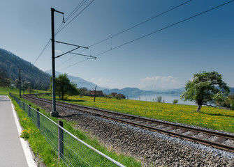 spring landscape with lake and mountains and train tracks in the foreground