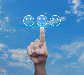 Hand pressing excellent smiley face rating icon over blue sky with white clouds, Business customer service evaluation and feedback rating concept