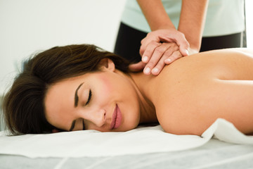 Obraz na płótnie Canvas Young woman receiving a back massage in a spa center.