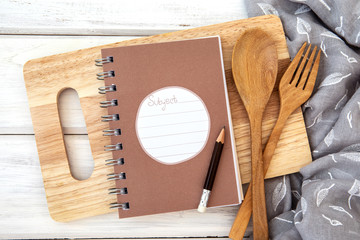 book notepad paper on a chopping cutting board and tablecloth on white table , recipes food  for healthy habits shot note background concept