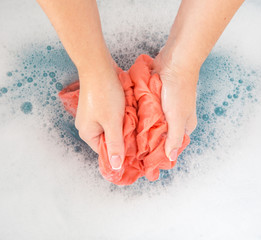 Female hands washing color clothes in sink