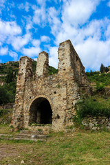 Fototapeta na wymiar Beautiful and romantic ruins of the stone medieval house with arch blue sky with clouds on the background, abandoned city Mystras, Peloponnese, Greece