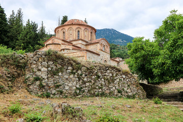 Fototapeta na wymiar beautiful old orthodox church behind the stone wall in abandoned medieval town Mystras, Greece
