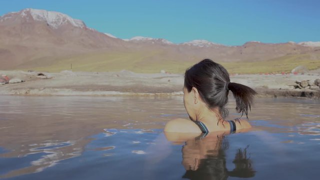 Woman taking a bath at El Tatio Geysers hot springs at Atacama desert, amazing thermal spring waters at 4500 masl inside Andes mountains scenic a place with an awe geothermal activity below the ground