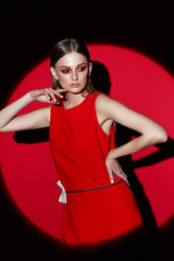 Fototapeta na wymiar Fashion portrait of young woman in red dress. red background, spotlight