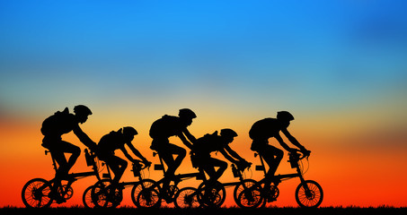 Silhouette group friend  and bike relaxing on blurry sunset background.