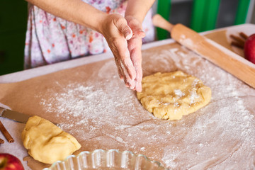 Hands working with dough preparation recipe bread. Female hands making dough for pizza. Woman's hands roll the dough. Mother rolls dough on the kitchen board with a rolling pin