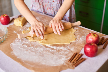 Woman kneading dough for the apple pie on kitchen table. Rustic style