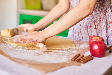 Obraz na płótnie Canvas Hands working with dough preparation recipe bread. Female hands making dough for apple pie. Woman's hands roll the dough. Mother rolls dough on the kitchen board with a rolling pin
