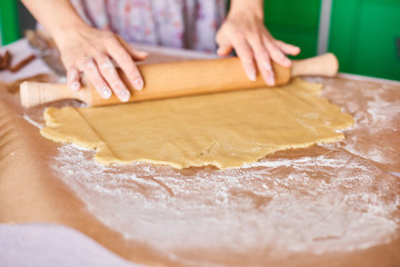 Hands working with dough preparation recipe bread. Female hands making dough for pizza. Woman's hands roll the dough. Mother rolls dough on the kitchen board with a rolling pin