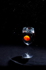 Transparent glass of water in the foreground on a black background