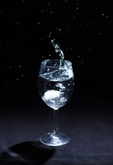 Transparent glass of water in the foreground on a black background