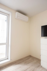 The air conditioner is installed in the corner of the real room next to the door to the balcony. The interior of the bedroom.