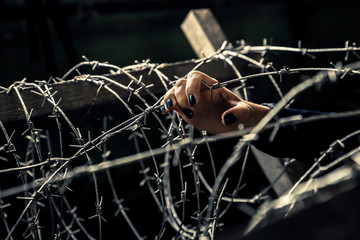 Woman's hand close up holding a barbwire. Blue, dark manicure.