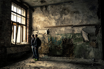Portrait of two, young people standing in ruined, old factory.