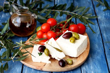 Fototapeta na wymiar Greek feta cheese, olives and cherry tomatoes on a wooden table