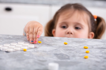Girl Taking Tablets From Worktop