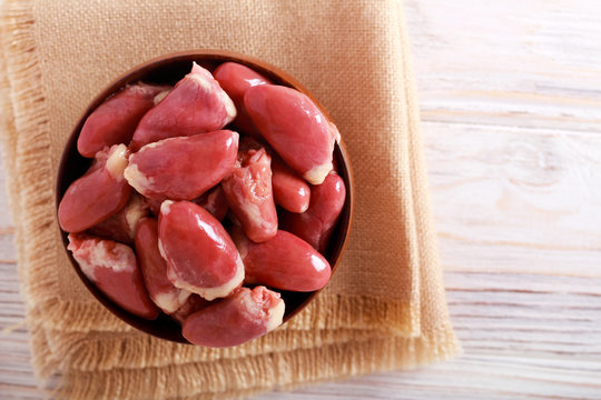 Raw chicken hearts in wooden bowl
