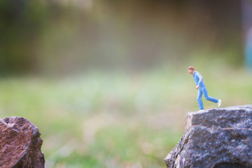 Miniature people : Running on rock cliff with nature background