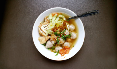 Indonesian traditional meatballs or bakso. Soup containing meatballs, noodles, fried tofu and cucumber pickles