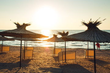 reed beach umbrellas of morning sunlight on sandy seashore.